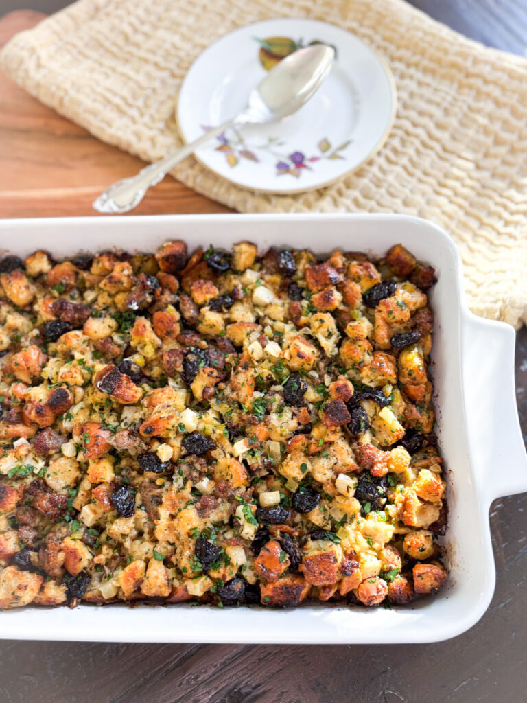 Sausage and herb stuffing with apples and dried cherries baked in a white casserole dish until golden brown and crisp on top.