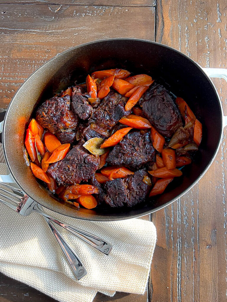 Tender pot roast with carrots in a Dutch oven, slow cooked until fork-tender.