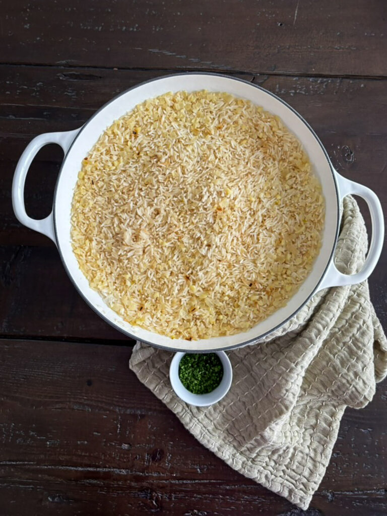 Simple rice pilaf in a white serving bowl with parsley garnish