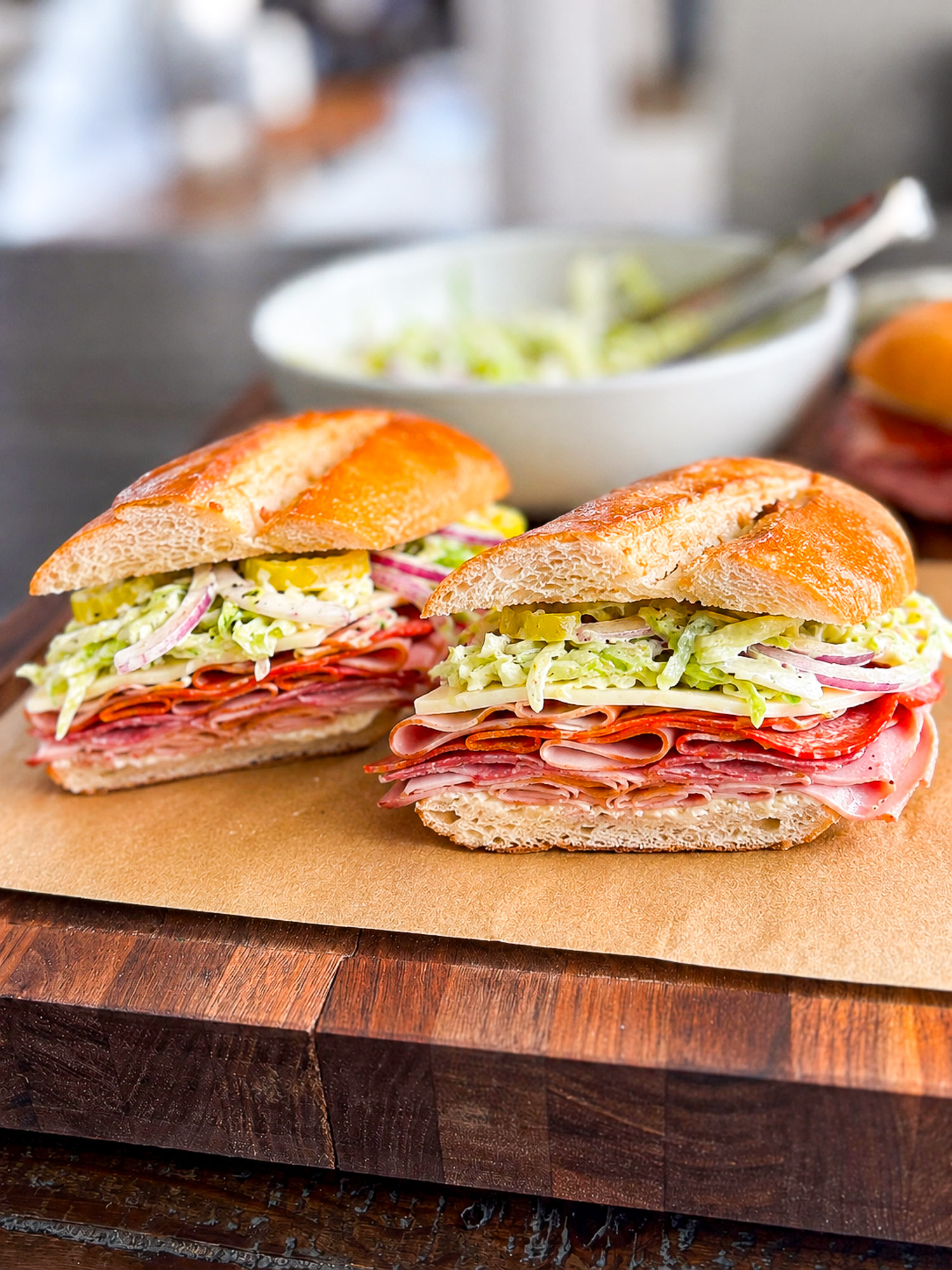 Italian grinder sandwich with creamy deli slaw, layered Italian meats, provolone, pepperoni, red onion, and banana peppers on a toasted sub roll.