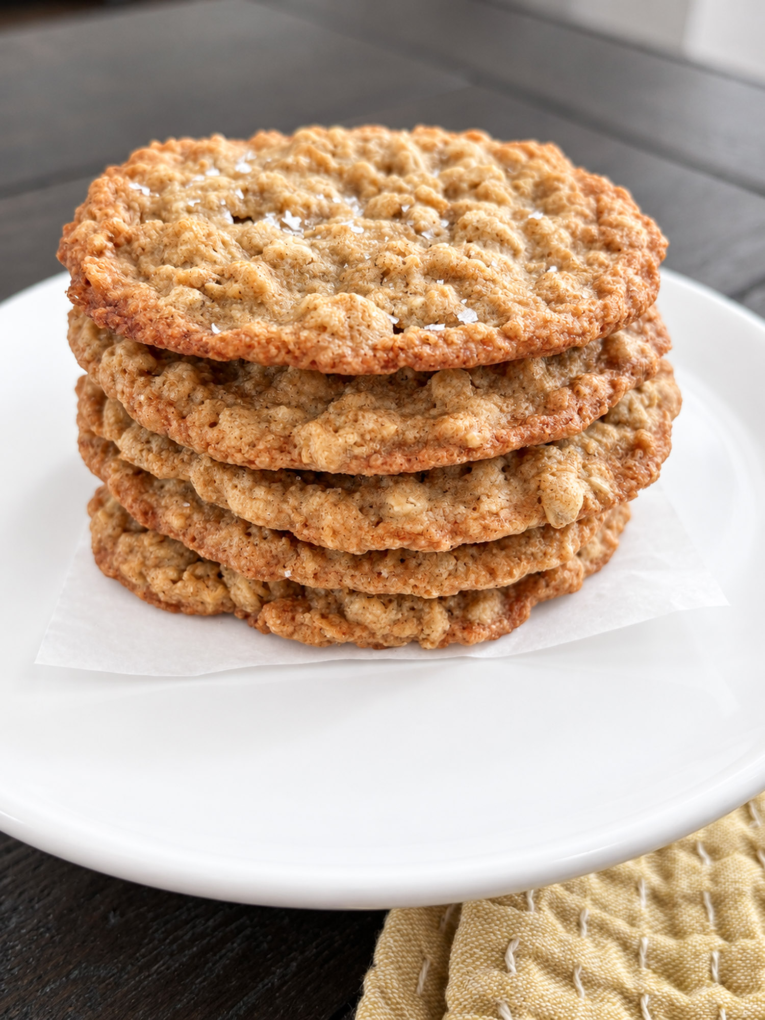 Thin and chewy oatmeal cookies stacked on a white plate